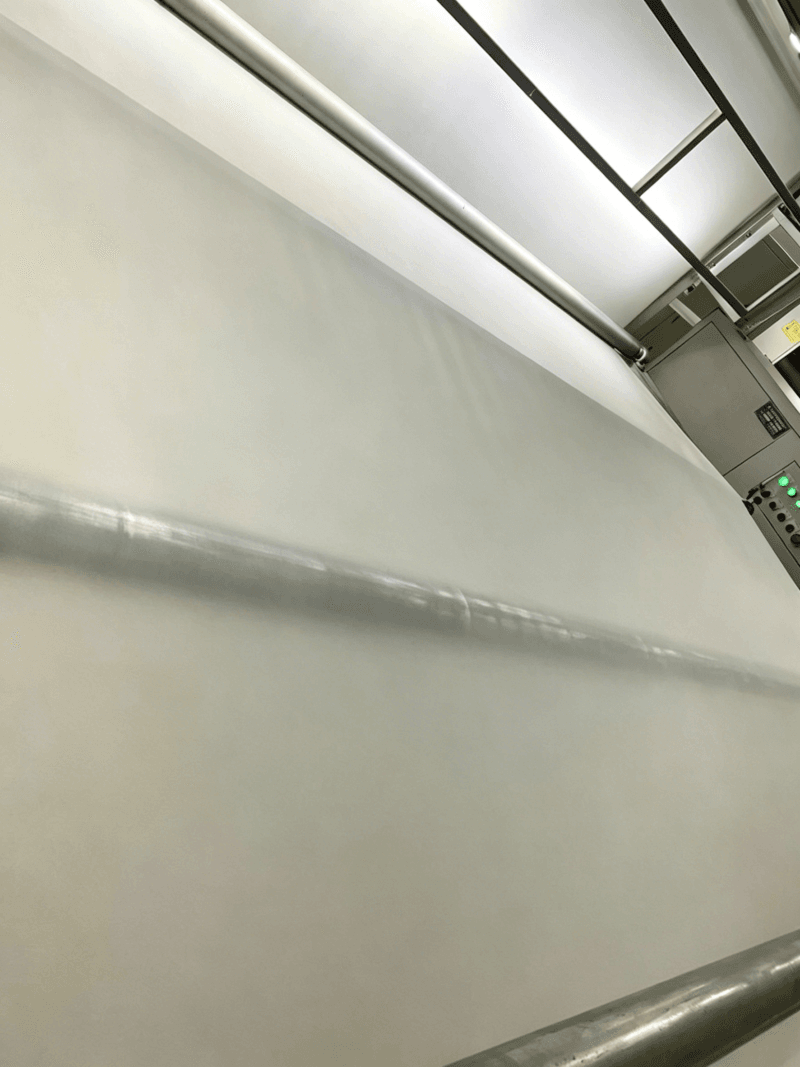 Industrial manufacturing line processing a large roll of white EVA interlayer film.